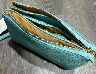 Teal clutch bag with gold interior on a wooden surface