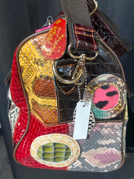 Multicolored textured handbag with decorative elements on a dark background