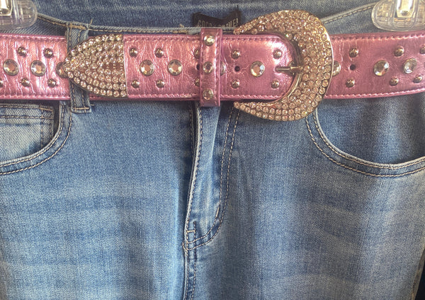 Close-up of blue jeans with a decorative pink belt featuring gold accents.
