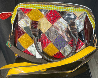 Multicolored patchwork handbag with a yellow strap on a dark surface