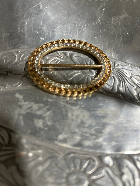 Close-up of a decorative metal t shirt clip with intricate designs on a metallic background