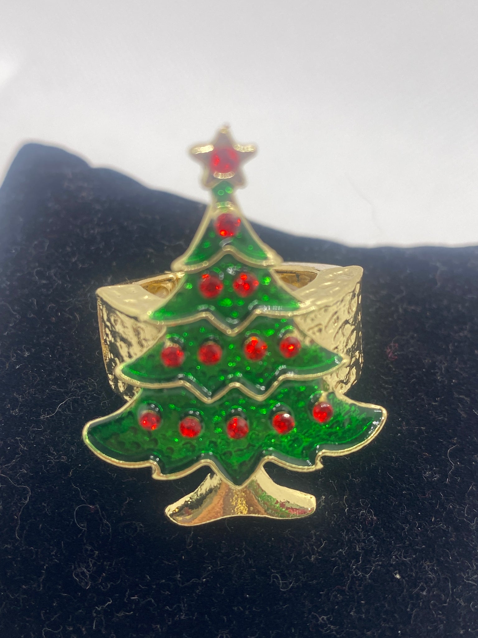 Christmas tree-shaped stretch ring with red berries on a black background