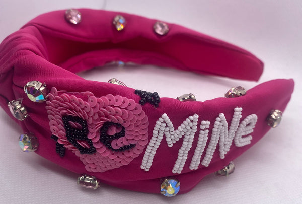 Pink headband with decorative elements and Be Mine text on a white background