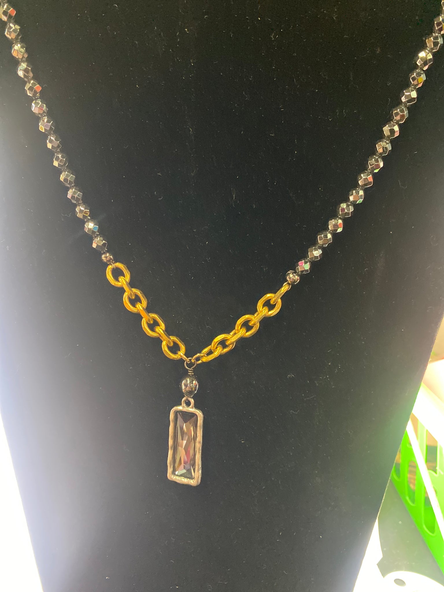 Gold chain with a rectangular pendant on a black background