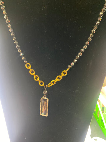 Gold chain with a rectangular pendant on a black background