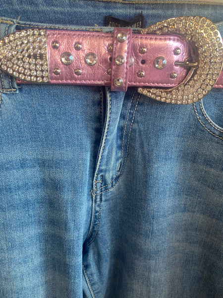 Close-up of a pink belt with decorative buckle on blue jeans