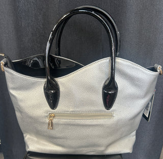 Silver handbag with black handle on a dark surface