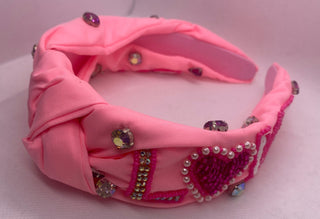 Pink headband with embellishments on a light pink background