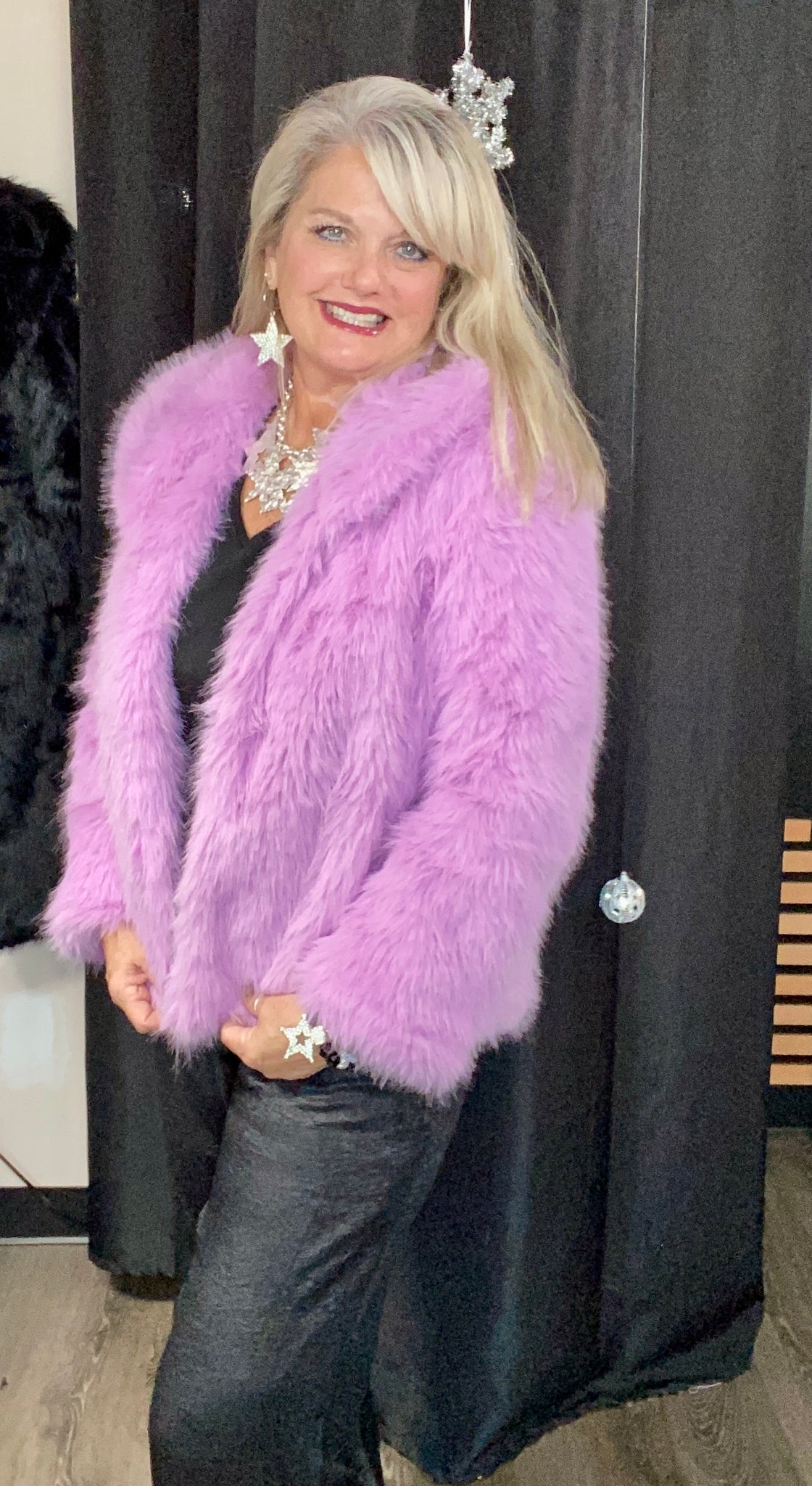 Woman wearing a pink Faux Fur coat against a black background
