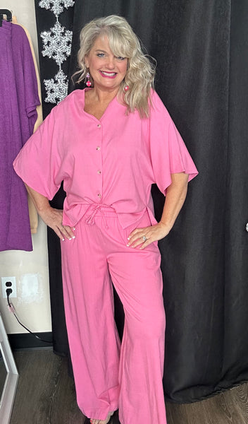 Woman wearing a pink outfit standing against a black background