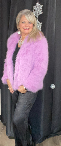 Woman wearing a pink fur coat against a black background