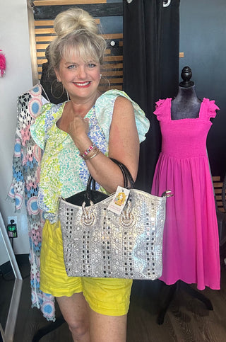 Woman holding a large handbag with a pink dress on a mannequin in the background