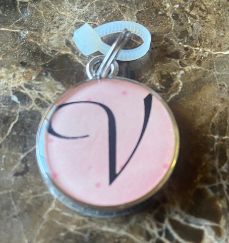 Pink Charm with 'V' monogram on a marble surface