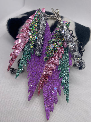 Multicolored glittery feather earrings on a mannequin head with fur.