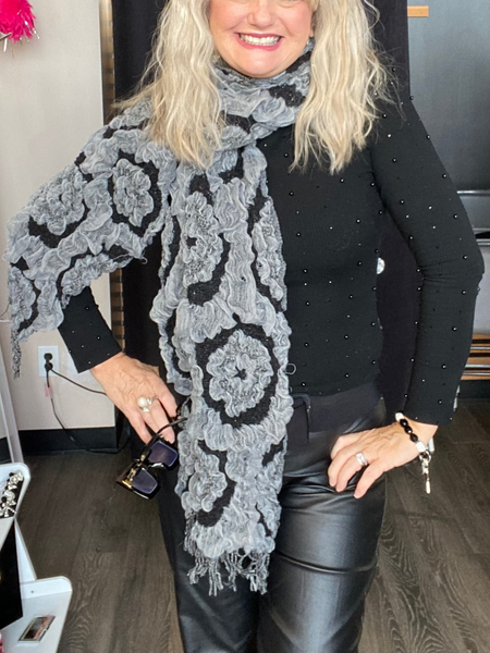 Woman wearing a black top and gray patterned scarf in a store setting