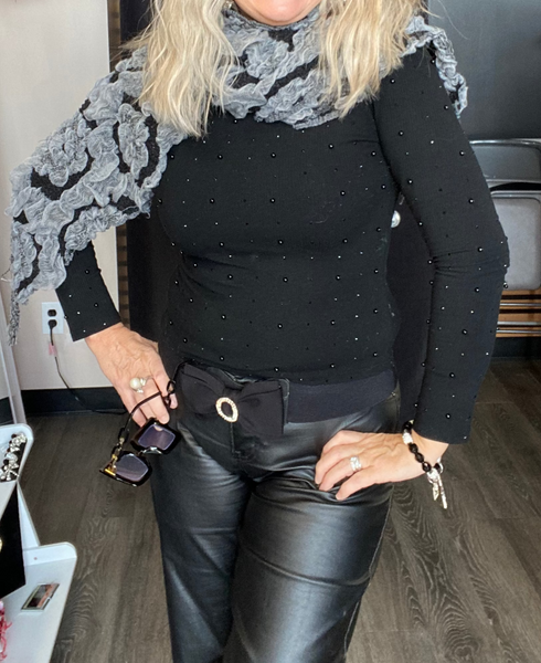 Woman wearing a black outfit with a gray scarf in a store setting