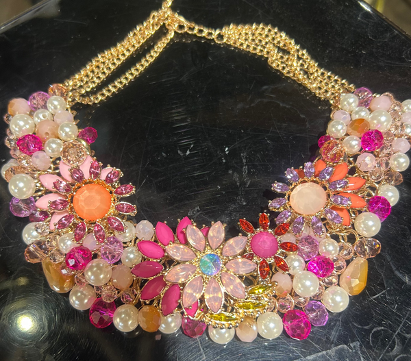 Decorative necklace with floral designs and colorful beads on a reflective surface