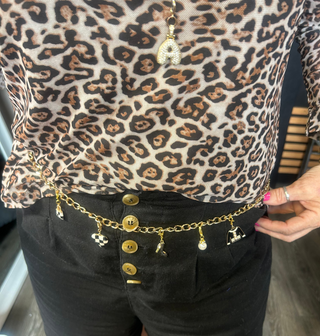 Person wearing a leopard print top and black shorts with a gold belt featuring charms.