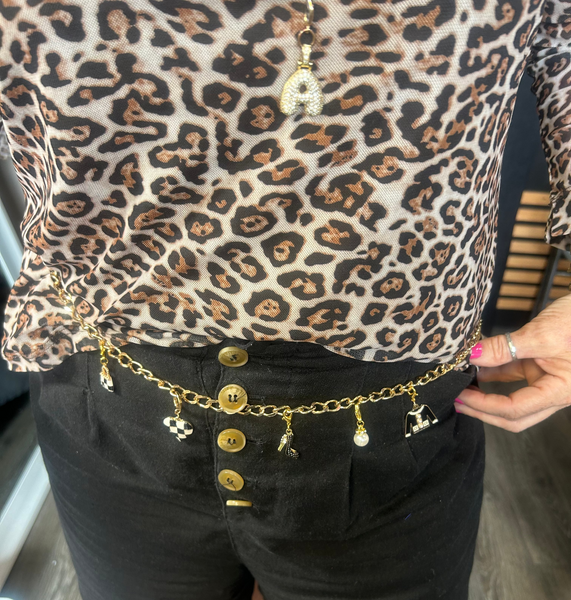 Person wearing a leopard print top and black shorts with a gold belt featuring charms.