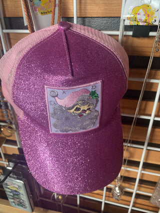 A pink glittery trucker hat with a Santa Claus patch on the front.