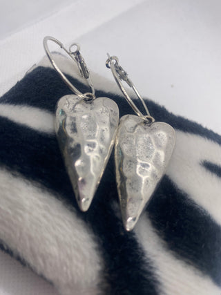 Silver heart-shaped earrings on a zebra-patterned background
