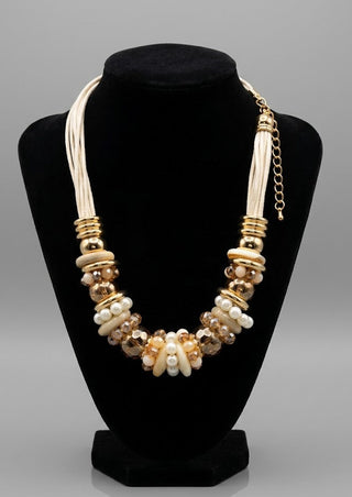 Necklace with gold and pearl beads on a black stand against a gray background