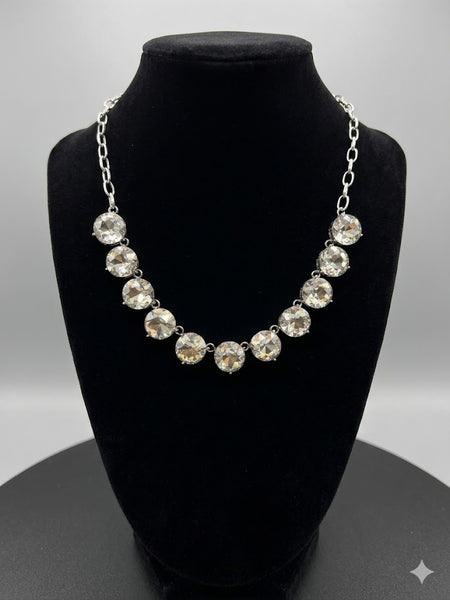 Necklace with large crystals on a black bust against a gray background