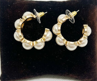 Pair of pearl hoop earrings on a black velvet cushion