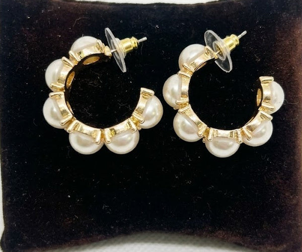 Pair of pearl hoop earrings on a black velvet cushion