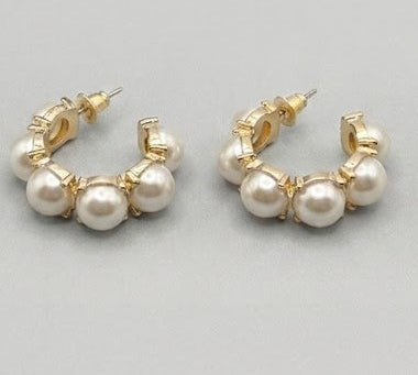 Pair of gold hoop earrings with pearls on a light gray background