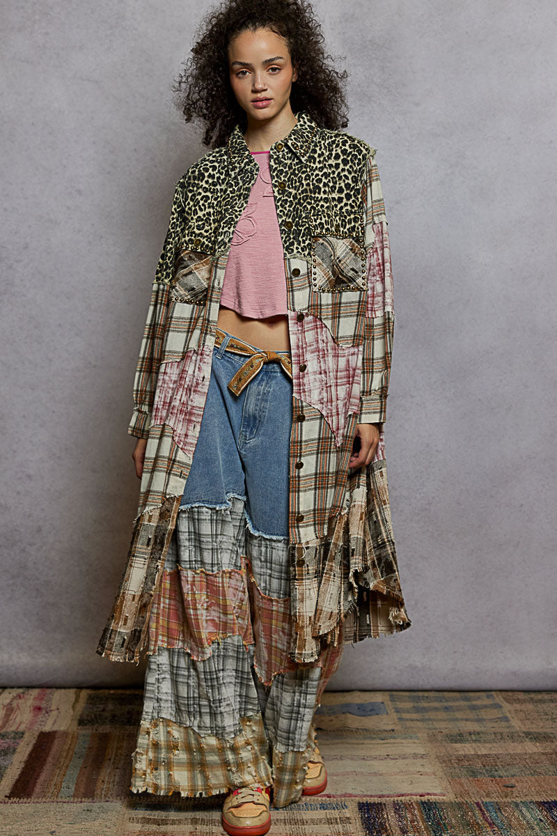 Woman wearing a layered, patchwork outfit with a leopard print jacket against a plain background