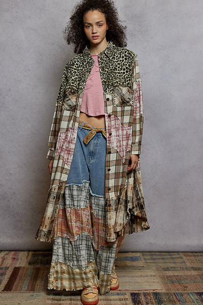 Woman wearing a layered, patchwork outfit with a leopard print jacket against a plain background