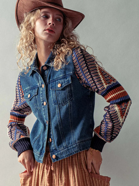 Person wearing a denim jacket over a patterned sweater with a plain background