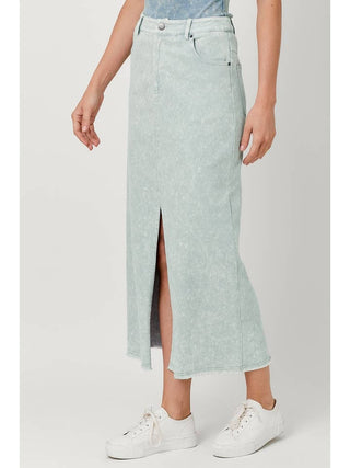 Person wearing a light green denim skirt with a white background