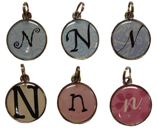 Round charm pendant with letter 'N' on a decorative background